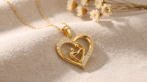 Gold-plated mother and child heart pendant necklace laid on a soft neutral surface