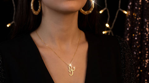 Gold heart initial pendant necklace and statement hoop earrings styled for a New Year's Eve night-out look