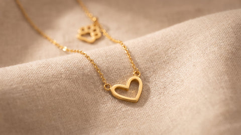 Dainty gold heart pendant styled near a paw-print motif