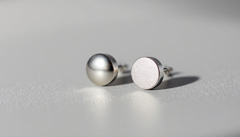 Two pairs of stud earrings side by side, illustrating how to tell genuine metal jewelry from base-metal costume pieces