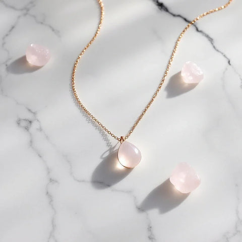 Delicate rose gold necklace with pale pink rose quartz pendant on marble — rose quartz meaning