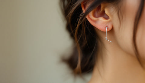 Close-up of a delicate safety-pin-shaped earring worn through a healed earlobe piercing