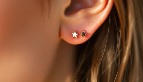 Close-up of a small gold star stud earring worn in an ear