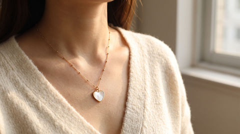 Small white shell heart pendant on a gold-plated sterling silver chain worn at the collarbone, a Sweet Alhambra heart look-alike