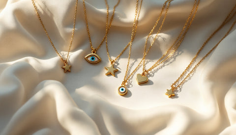 Delicate gold and silver evil eye, star, and heart charm necklaces arranged on a linen surface
