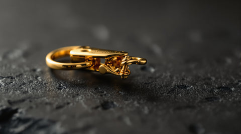 Macro photograph of an open lobster clasp jewelry mechanism showing the trigger and spring