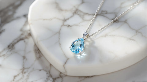 Blue topaz pendant necklace on white marble with sterling silver setting