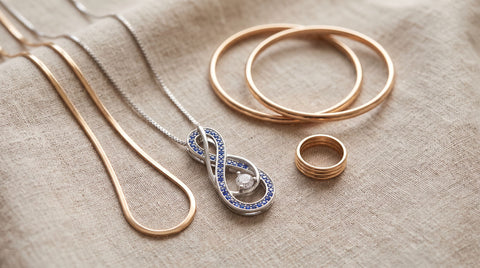Turquoise infinity pendant necklace styled with gold chains, bangles, and a ring