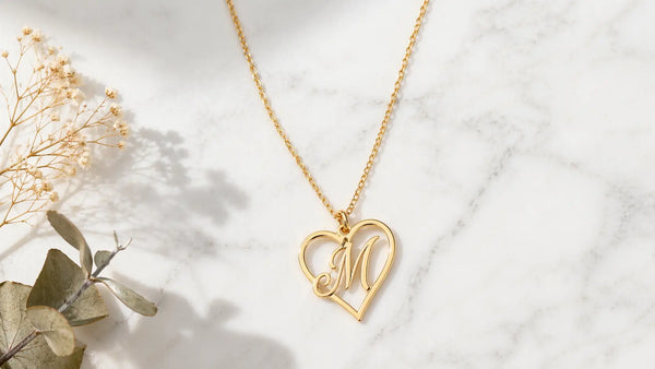 Gold plated heart initial necklace on white marble — personalized jewelry symbolizing love
