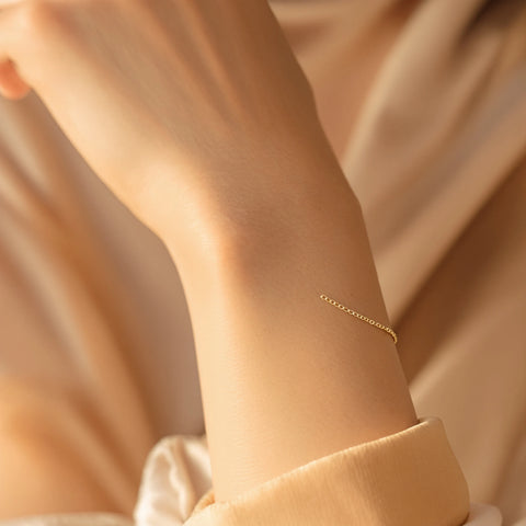 Permanent jewelry — delicate gold welded bracelet with no clasp on a woman's wrist