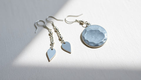 Silver tone dangle earrings and a round hammered pendant on pale linen