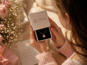 Young woman opening AJLuxe jewelry gift box with pink heart earrings and gold necklace for a thoughtful gift for daughter