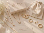 Flat lay of AJLuxe dainty gold jewelry and gift pouch styled as affordable luxury gifts under $50