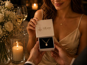 Woman receiving AJLuxe jewelry gift box with gold necklace during a romantic candlelit evening gift moment for wife