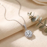 Load image into Gallery viewer, Round Halo Pendant Necklace lifestyle flat lay on linen with eucalyptus, rhodium plated finish
