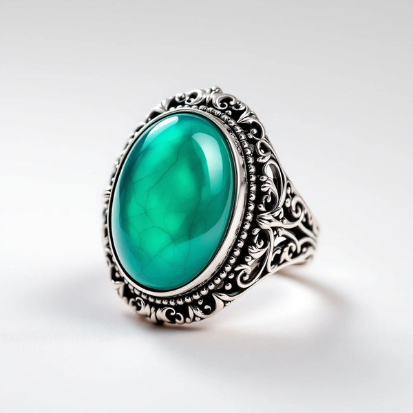 Color-changing mood ring with ornate filigree band and teal thermochromic stone — white background