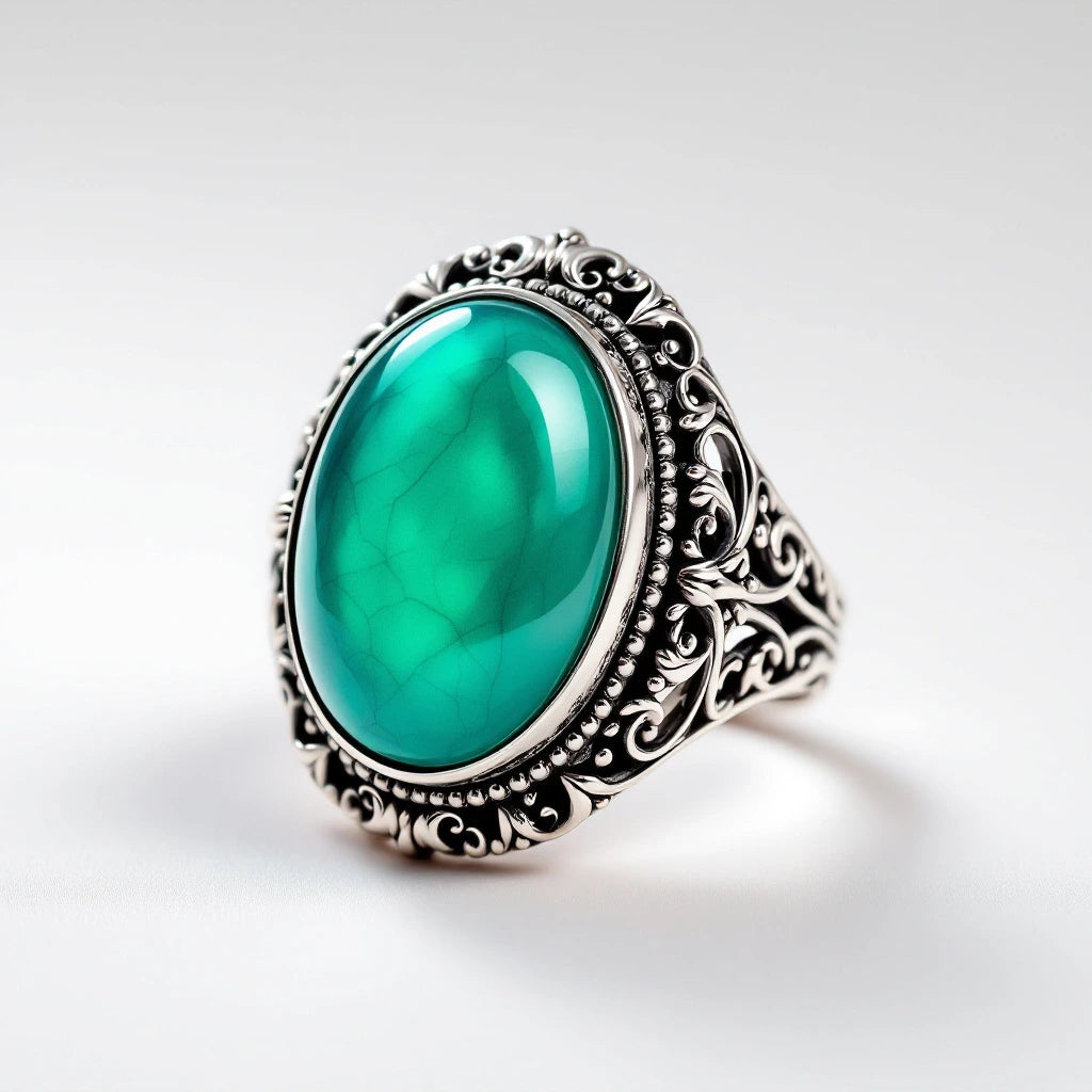 Color-changing mood ring with ornate filigree band and teal thermochromic stone — white background