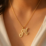 Load image into Gallery viewer, Heart initial necklace in 18K gold plated sterling silver — personalized script M pendant with heart detail, worn on model
