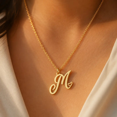 Heart initial necklace in 18K gold plated sterling silver — personalized script M pendant with heart detail, worn on model