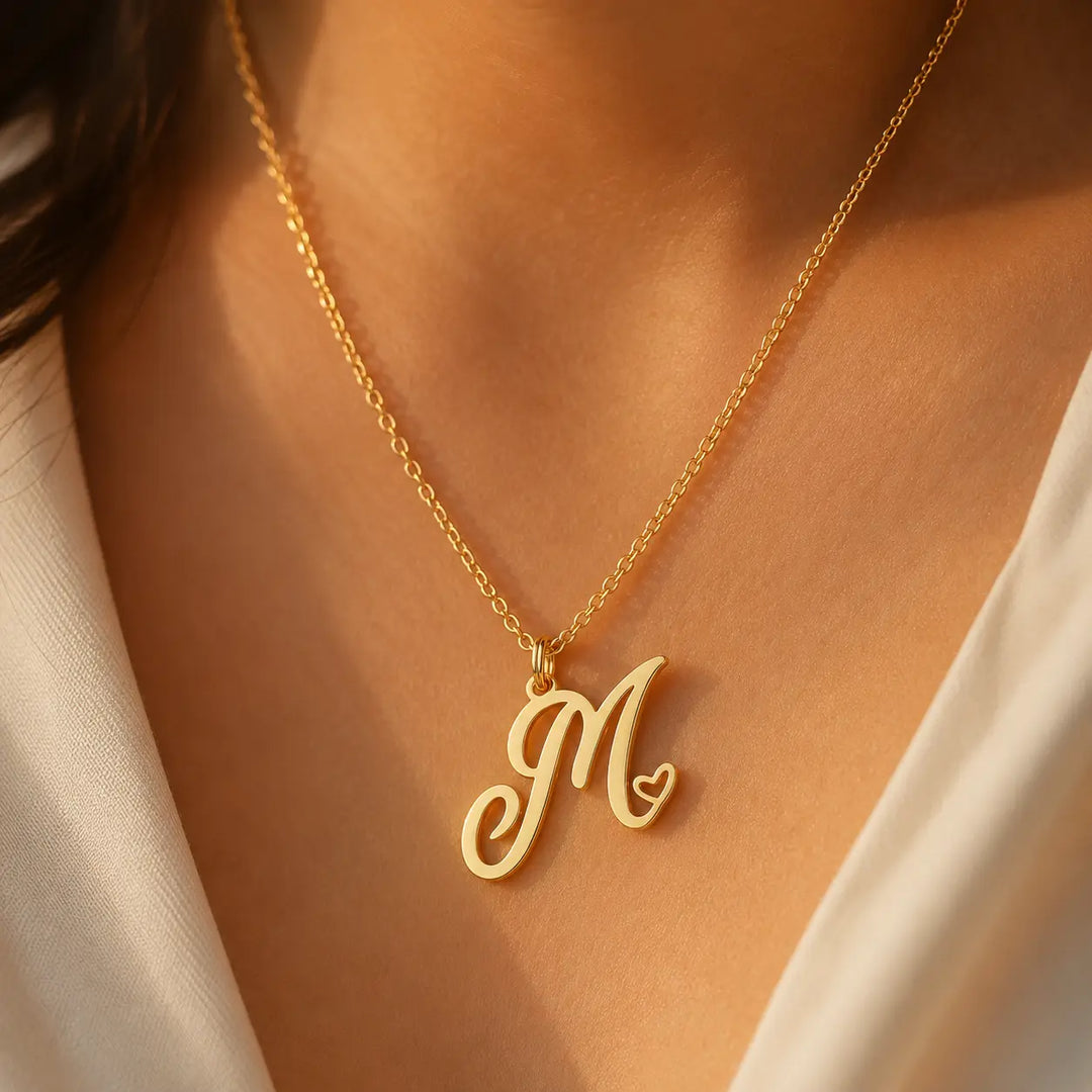 Heart initial necklace in 18K gold plated sterling silver — personalized script M pendant with heart detail, worn on model