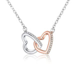 Lade Bild in die Galerieansicht, Interlocking Hearts Necklace, real product photo, two-tone pendant with an imitation rhodium CZ pave heart interlocked with a rose gold plated heart, on a curb chain, white background
