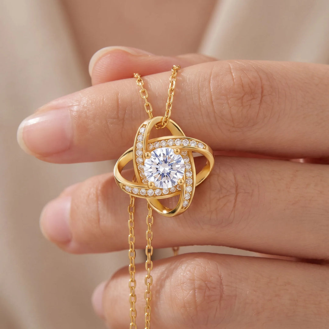 Love Knot Necklace held close-up showing the CZ center stone and pave detail, 18K gold plated finish