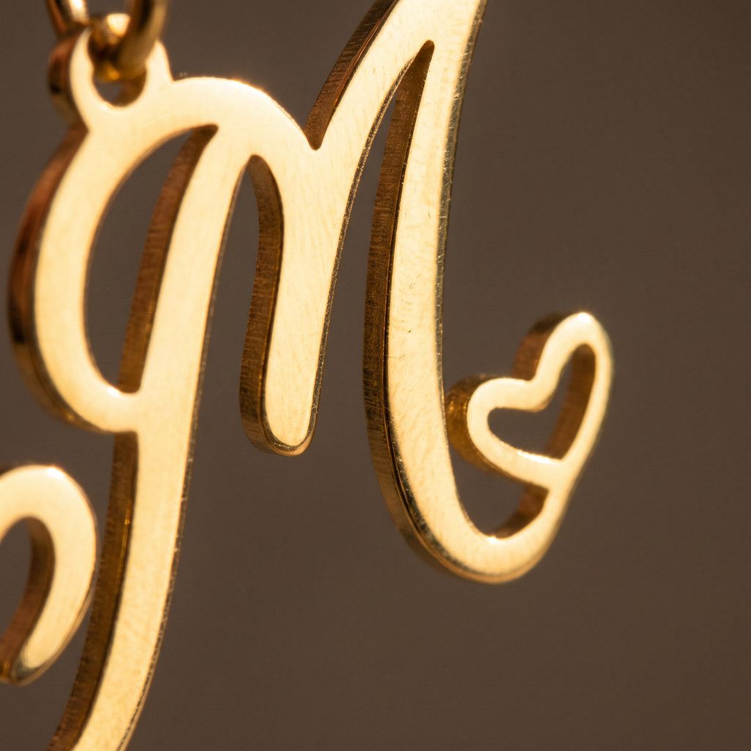 Macro close-up of the 18K gold plated finish on a heart initial necklace charm in raking light