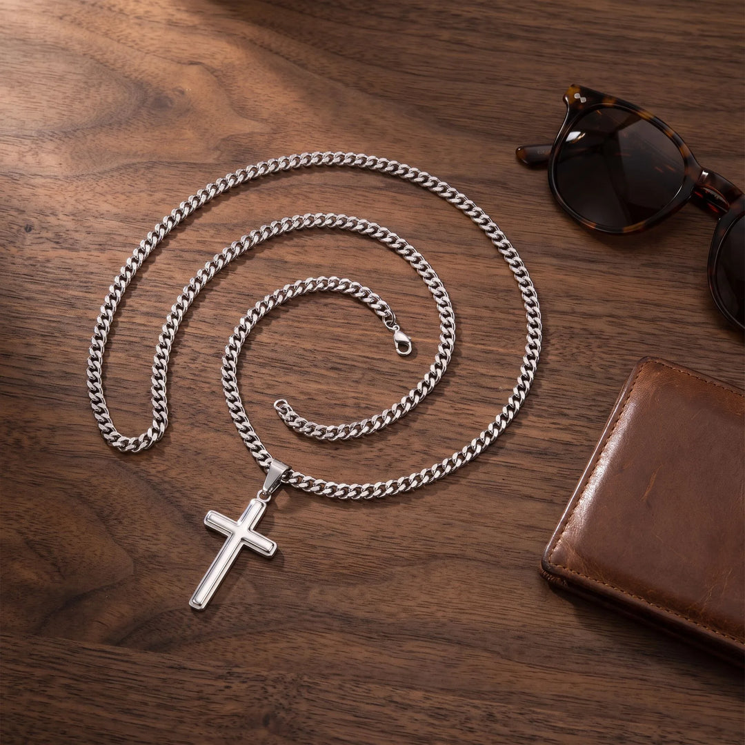 Men's stainless steel cross necklace flat lay with sunglasses and leather wallet