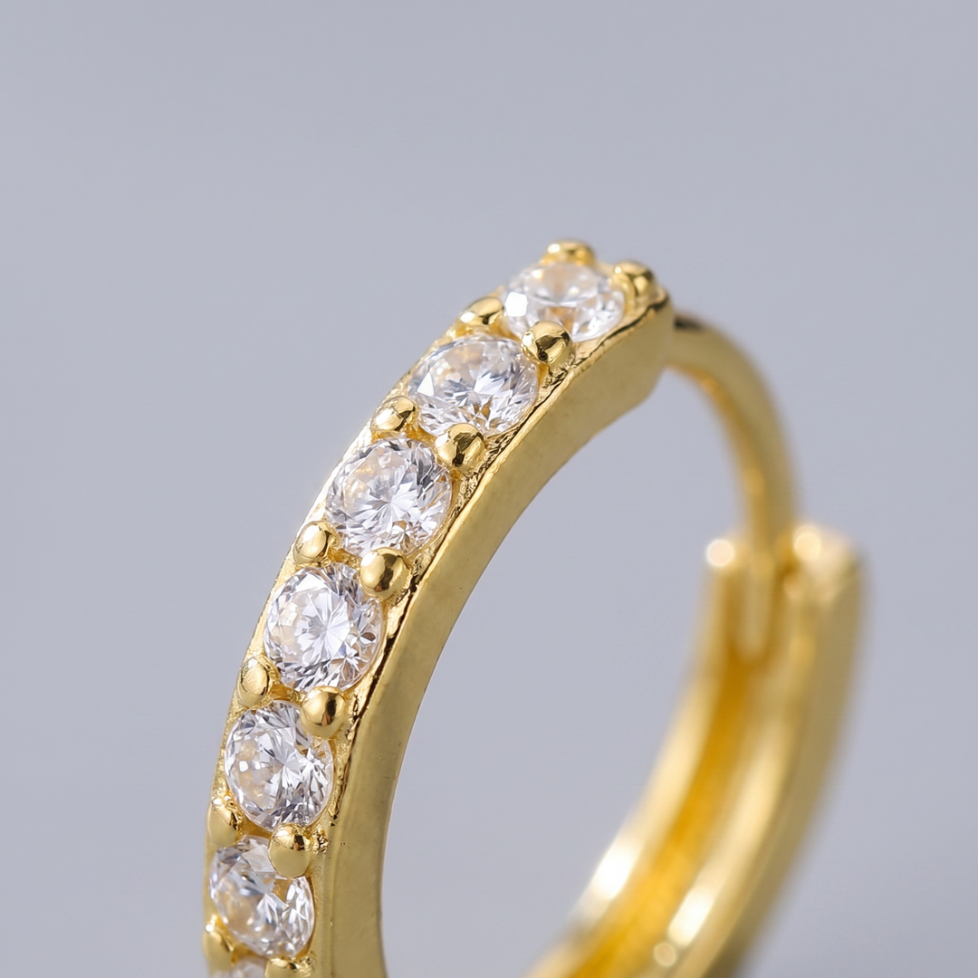 Macro close-up of a gold micro pave CZ huggie hoop earring showing the row of pave-set stones across the front arc