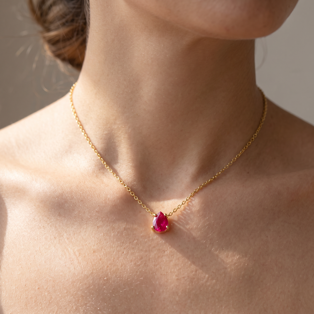 Ruby-red teardrop pendant necklace worn at the collarbone in natural daylight — 18K gold plated 925 sterling silver