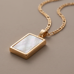 Load image into Gallery viewer, Macro close-up of a genuine mother-of-pearl rectangular pendant in an 18K gold plated bezel on a figaro chain
